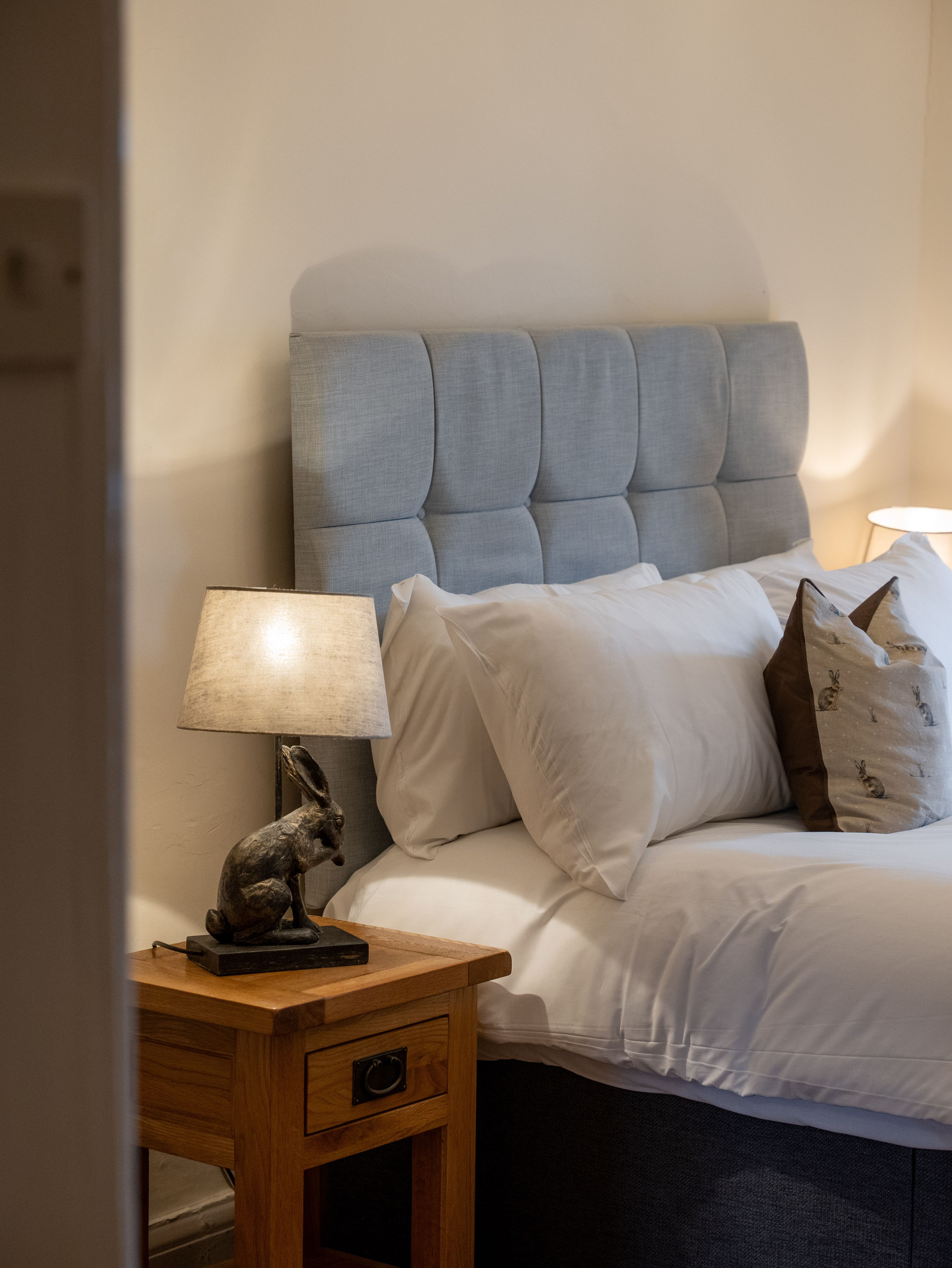 Bed next to a rabbit lamp on a bedside table