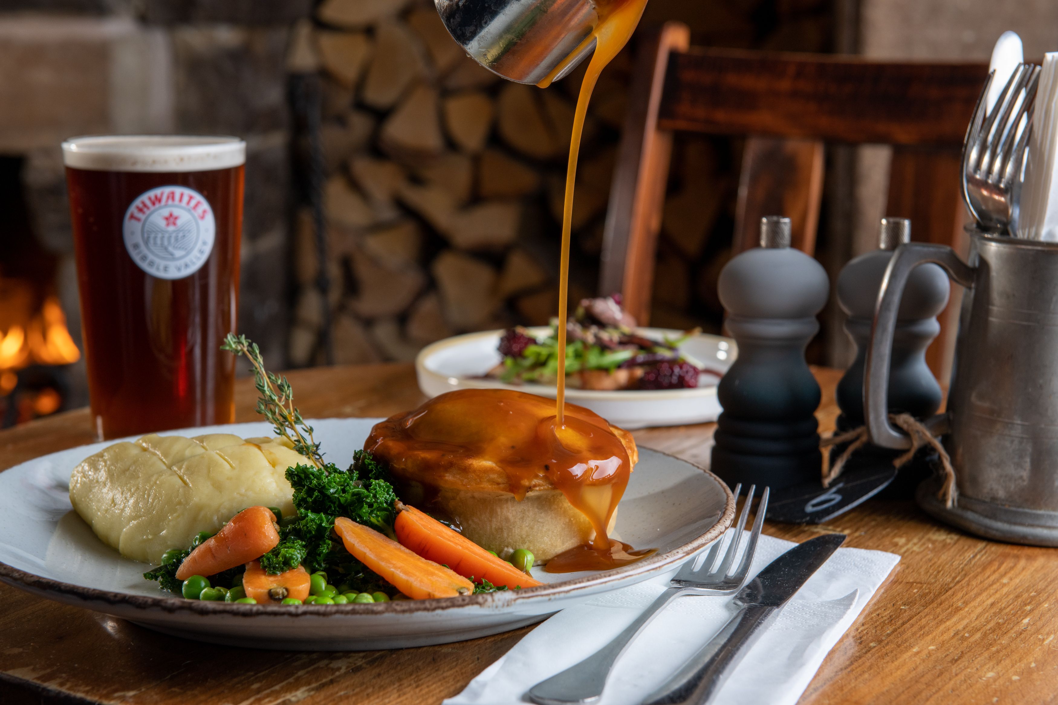 Gravy being poured over pie, mash, vegetables